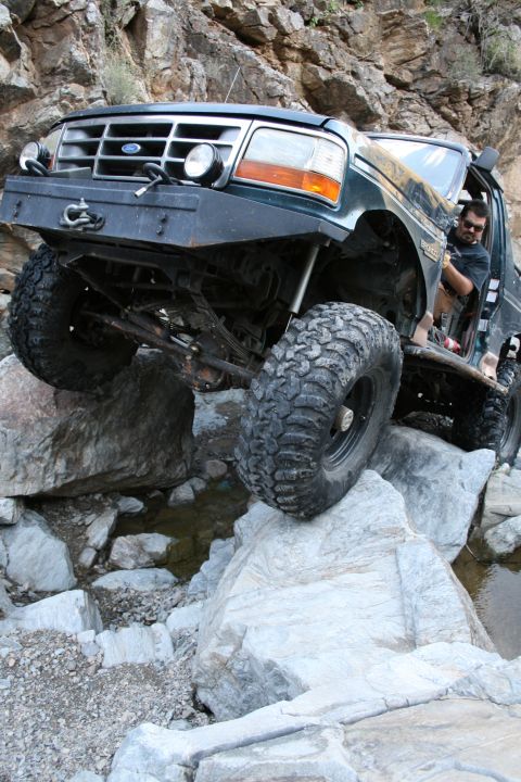1966 Ford Bronco - A modified Ford F-150 navigates a rocky trail with a driver visible.