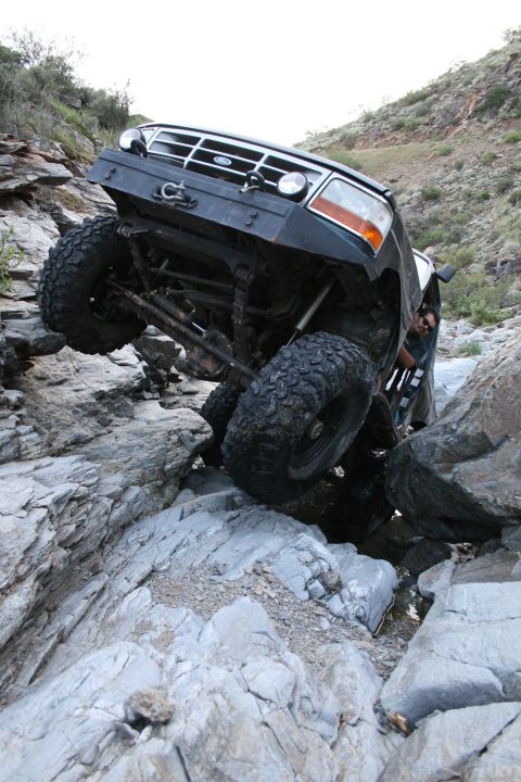 1966 Ford Bronco - A modified Ford Bronco is shown climbing over large rocks on a off-road path.