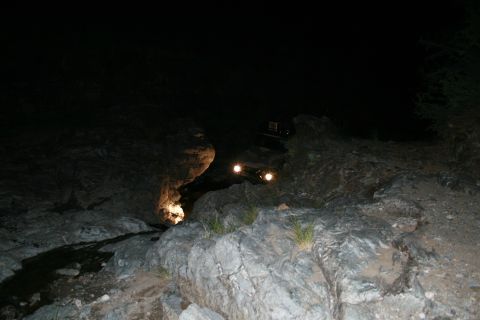 1966 Ford Bronco - Vehicle navigates a dark, rocky path at night, illuminated by its headlights.