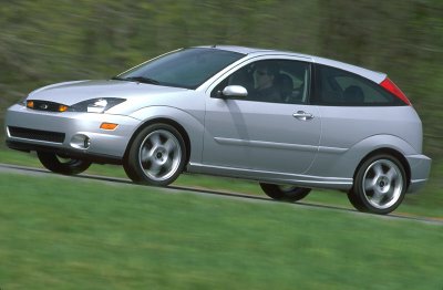 2002 Ford Focus - A silver 2002 Ford Focus hatchback is captured in motion on a grassy roadside.