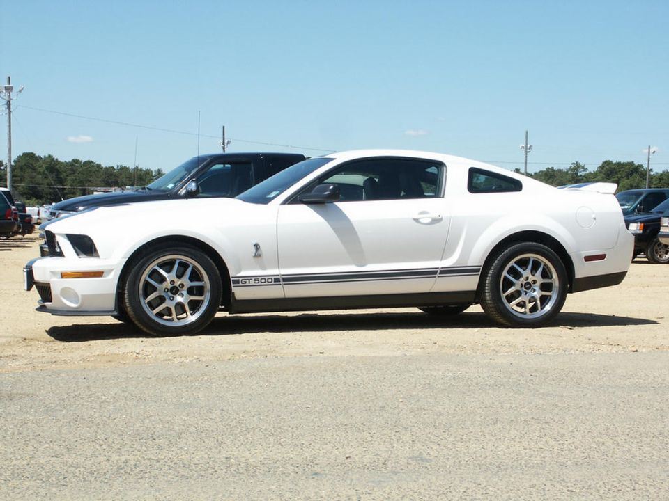 White Ford Mustang GT500 parked next to a black truck