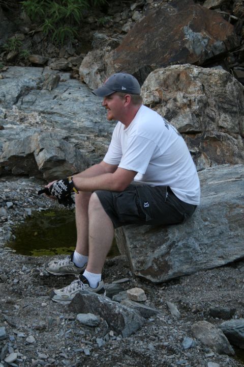 1966 Ford Bronco - Man sits on a rock in a rocky, outdoor environment.