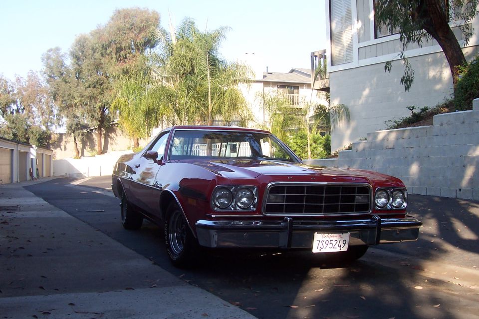 Dark red Ford Ranchero, front 3/4 view, chrome bumper and wheels, California plate, palm trees behind