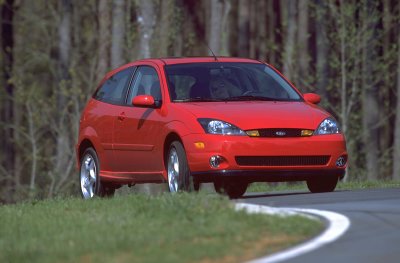 2002 Ford Focus - A red 2002 Ford Focus SVT hatchback is shown from a three-quarter front view on a road with trees behind it.