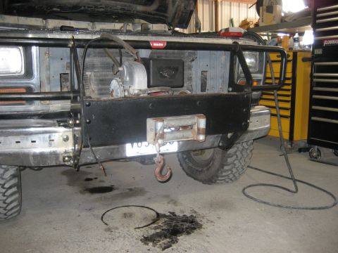 1986 Ford Bronco - The front of a 1986 Ford Bronco is shown with a winch and brush guard installed, parked indoors.
