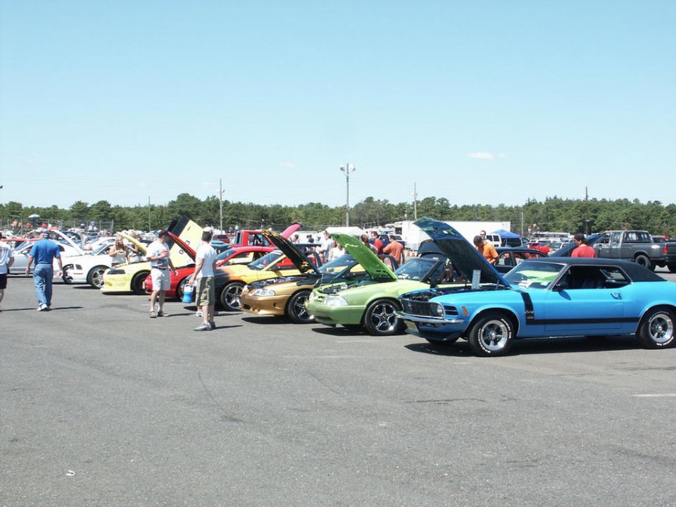 Blue 1970 Ford Mustang Boss 302 with black vinyl top and hood scoop, parked at a car show