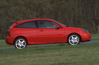 2002 Ford Focus - A red 2002 Ford Focus SVT is shown from the side, driving on a road with a grassy shoulder.