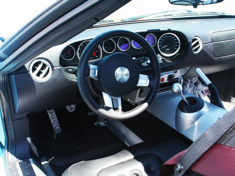 Interior of a Ford GT, showing the steering wheel with 'FORD GT' logo, dashboard gauges, and shifter
