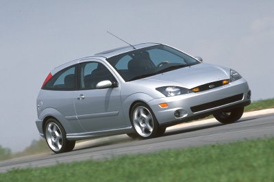 2002 Ford Focus - A silver 2002 Ford Focus SVT is captured in motion on a paved road with grassy shoulders.
