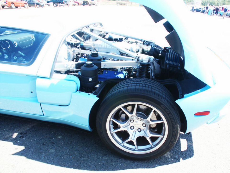 Light blue sports car engine bay with open hood and exposed engine components