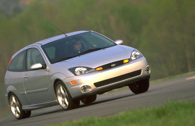 2002 Ford Focus - Silver 3-door hatchback with a driver visible through the windshield.