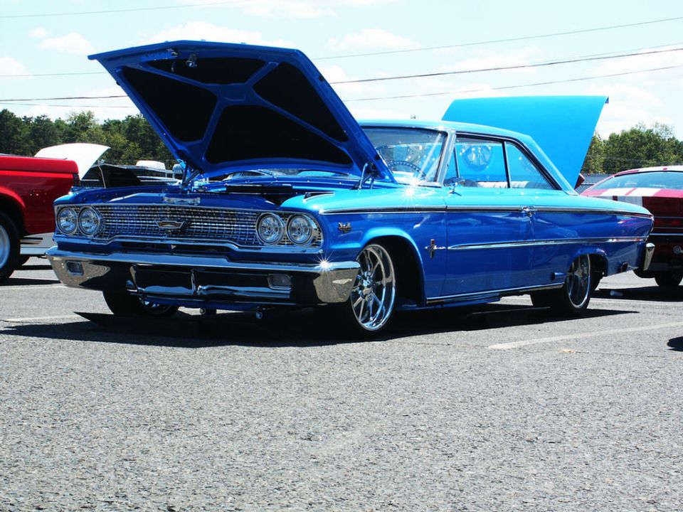 blue classic car with hood open, parked at an outdoor event