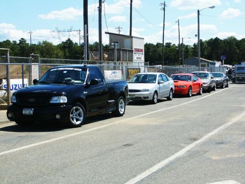 2001 Mercury Grand Marquis - A line of vehicles at a car show, led by a black 2001 Ford F-150 SVT Lightning pickup truck.