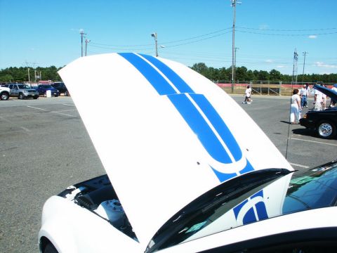 2001 Mercury Grand Marquis - A white 2001 Mercury Grand Marquis with blue racing stripes on its open hood at a car show.
