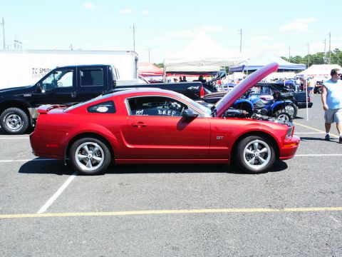 2001 Mercury Grand Marquis - A red Ford Mustang GT is parked at an outdoor event with its hood open, showing the engine bay.