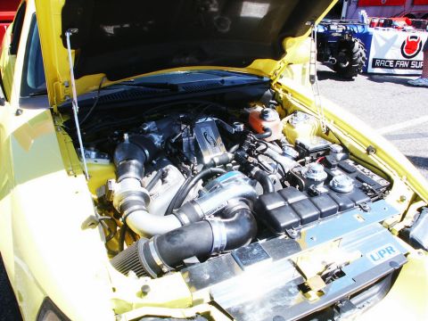 2001 Mercury Grand Marquis - Customized engine bay a turbocharger setup. The car is yellow and the hood is open.