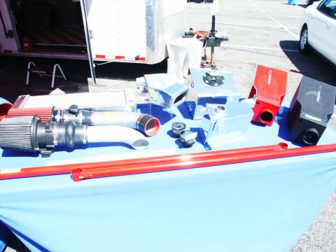 2001 Mercury Grand Marquis - A collection of automotive performance parts, such as superchargers and fluid tanks, are displayed on a table at an outdoor event.