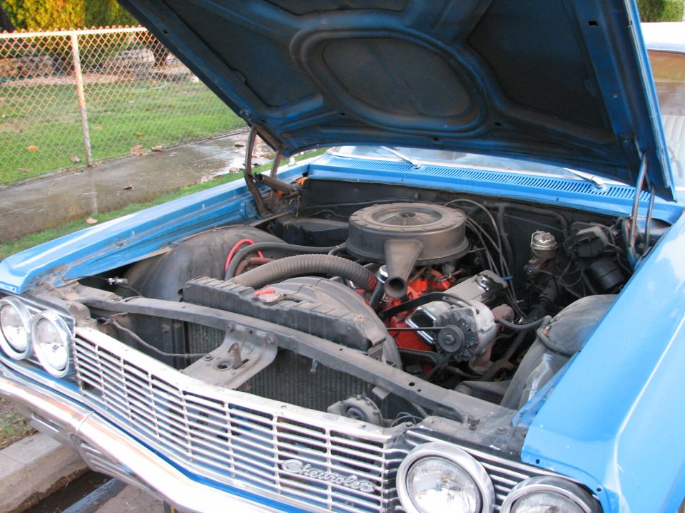 Blue Chevrolet with hood open showing engine. Grille says Chevrolet