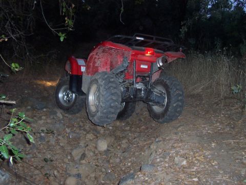 1994 Ford F-150 - A red ATV navigates a challenging, rocky path in a wooded area at dusk.