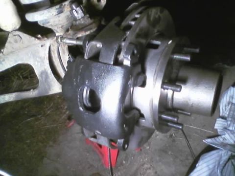 1989 Ford Bronco - Close-up of a front brake caliper and rotor assembly, possibly undergoing maintenance or repair.