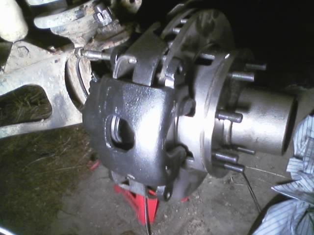 Front brake caliper and rotor assembly on a red jack