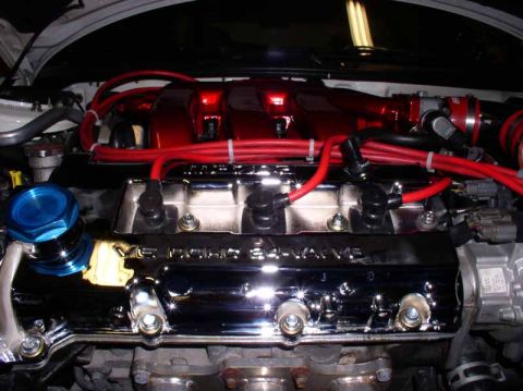 1996 Ford Probe - Close-up of an engine bay showing chrome valve covers and red spark plug wires.