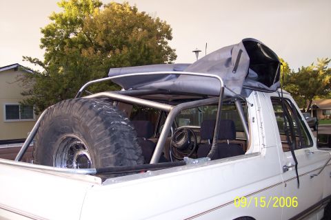 1989 Ford Bronco - 1989 Ford Bronco interior shows roll cage and spare tire mounted in the bed.