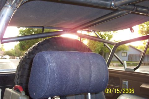 1989 Ford Bronco - The interior of a vehicle is shown with a prominent roll cage and a spare tire visible.
