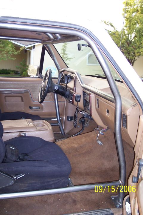 1989 Ford Bronco - The interior of a vehicle is shown with a prominent roll cage installed.
