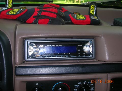 1996 Ford Bronco - The dashboard of a vehicle features a JVC stereo and a pair of red racing gloves resting on top.