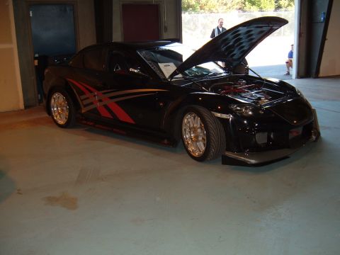 1991 Ford Probe - A black sports car with custom graphics is parked indoors with its hood open.