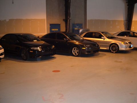 1991 Ford Probe - Multiple sedans are parked in a dimly lit garage, with a silver sedan in the foreground.