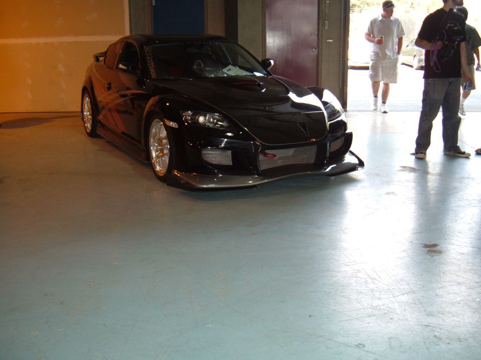 Black sports car with custom body kit and aftermarket wheels parked indoors