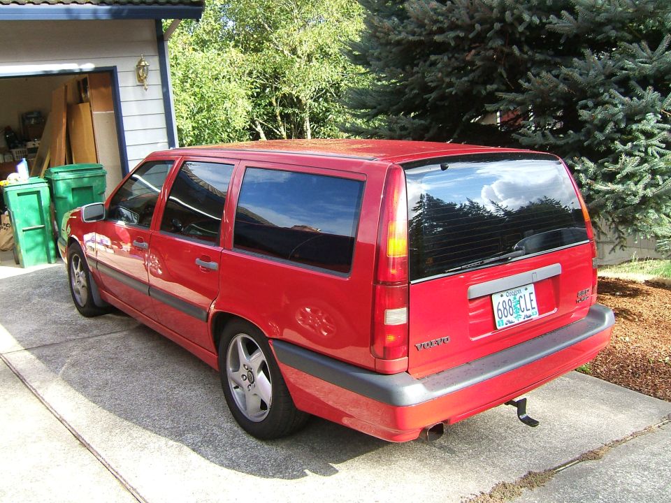 Red Volvo station wagon parked in driveway, rear 3/4 view