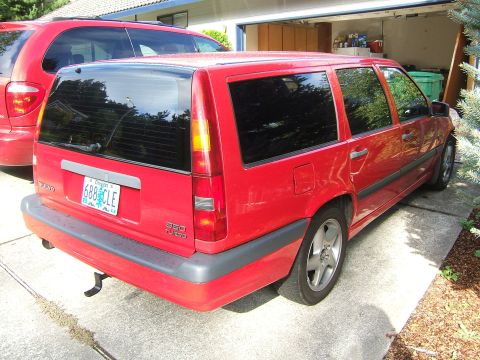 1987 Volkswagen Golf - This red Volvo wagon is parked in a driveway next to a red minivan.