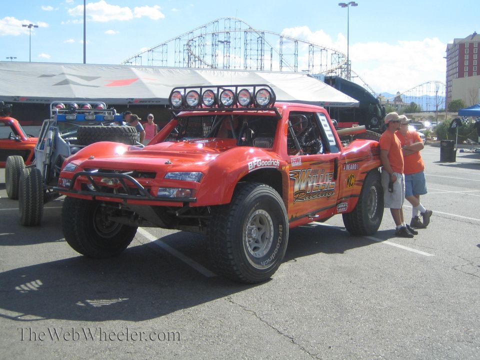 Orange off-road race truck with roof light bar parked at an event