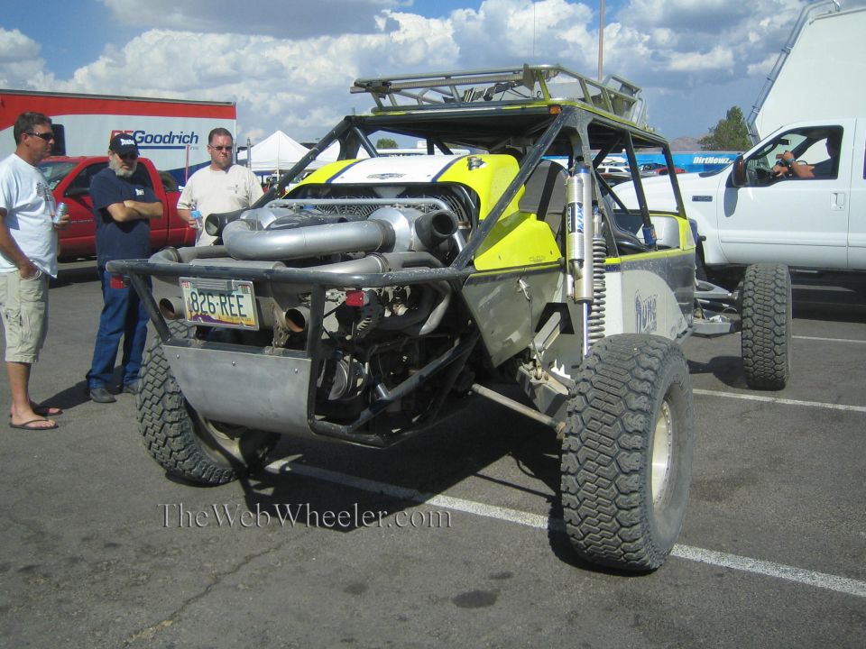Front view of an off-road race buggy with twin turbos and onlookers