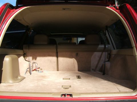 1987 Volkswagen Golf - The cargo area of a red SUV is shown, with tan carpeting and folded rear seats.