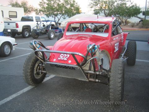 1990 Ford Bronco - red Volkswagen Beetle-bodied Baja race car, number 502, with exposed long-travel suspension and BFGoodrich skid plate in a paved lot.