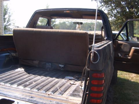 1988 Ford Bronco - The interior of the SUV shows a folded rear seat and the open truck bed, with an antenna visible on the exterior.
