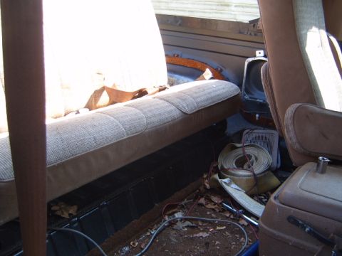1988 Ford Bronco - The interior of a vehicle with worn seats and debris on the floor, suggesting a model year around 1980.