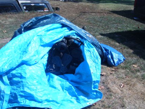 1988 Ford Bronco - Engine parts are covered by tarps in a grassy outdoor area.