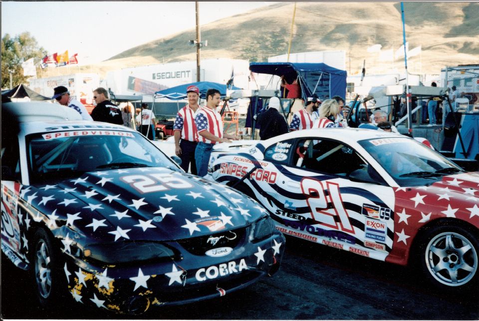 Two Ford Mustangs with stars and stripes livery, one with "COBRA" text and number 25, the other with number 21