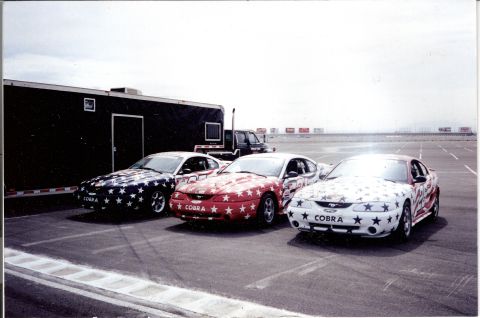 1995 Ford Mustang - Three 1995 Ford Mustangs, all painted with patriotic star and stripe designs, are parked together on a track.