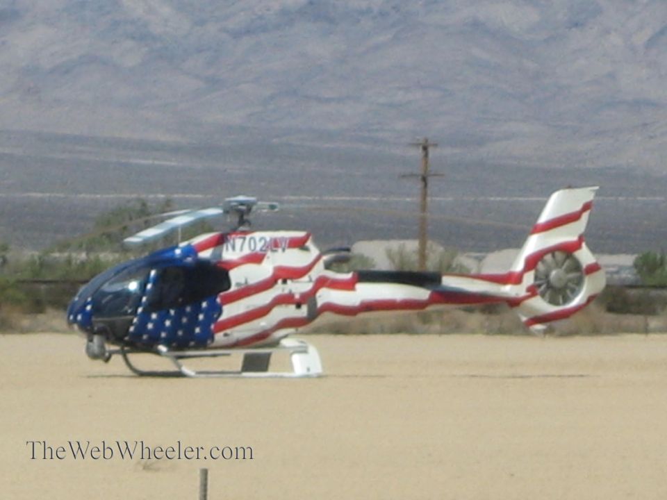 American-flag-painted helicopter on desert ground, registration N702LV