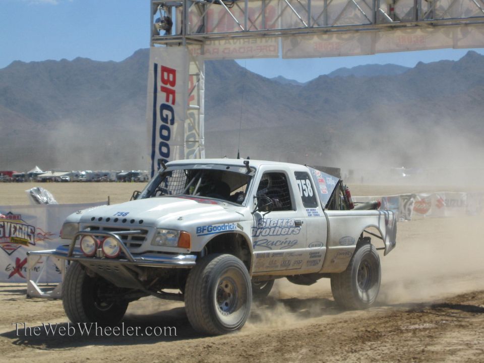 White #758 off-road race pickup truck racing in the desert dust