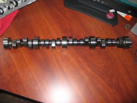 1991 Ford Bronco - A camshaft with multiple lobes and bearings is shown on a wooden surface.