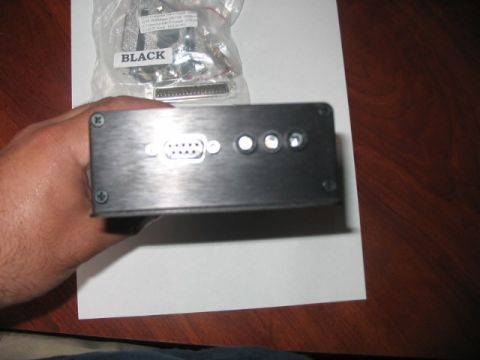 1991 Ford Bronco - A black electronic device with a DB9 serial port and four indicator lights is held in a hand, with a bag of connectors in the background.