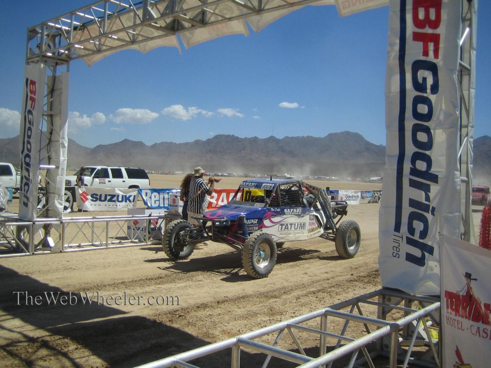 Off-road buggy passing under BFGoodrich arch with photographer in desert