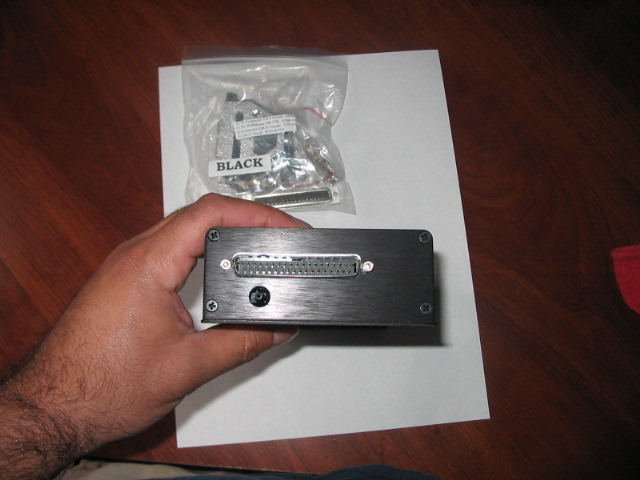 Black electronic device with a large connector and a bag of cables labeled "BLACK"